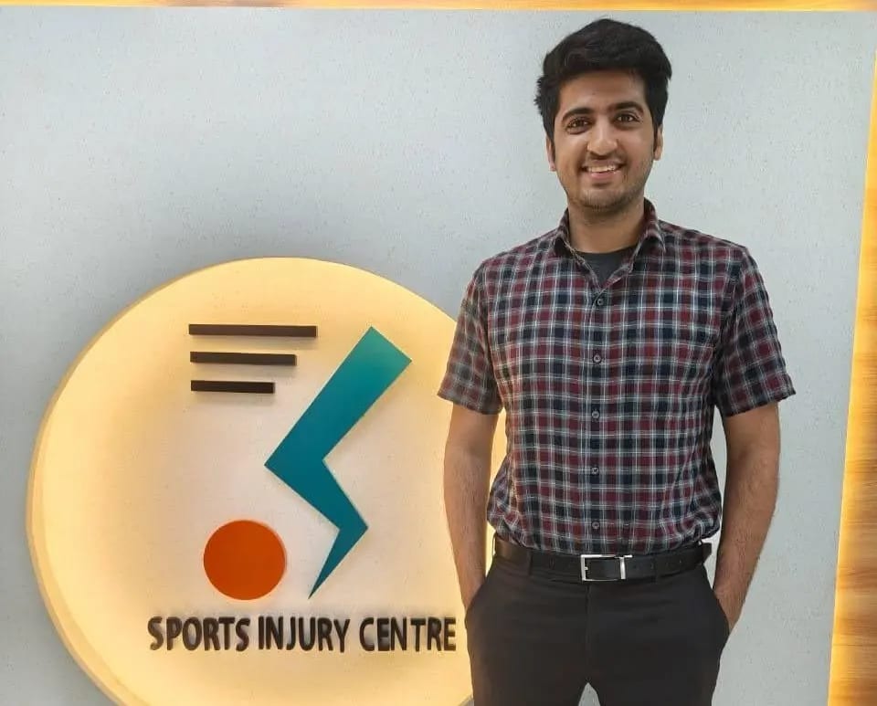 Dr. Dipen Ariwala beside the Sports Injury Centre signage